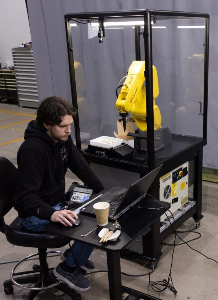 Image showing Chace Hutchins programming the FANUC Robot Demo